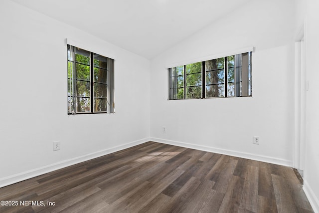 spare room with plenty of natural light, dark wood-type flooring, baseboards, and vaulted ceiling
