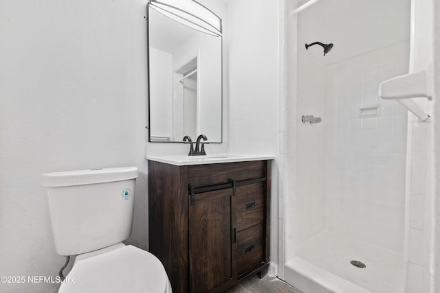 bathroom featuring toilet, a tile shower, and vanity