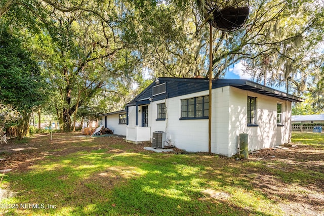 back of property featuring cooling unit and a lawn