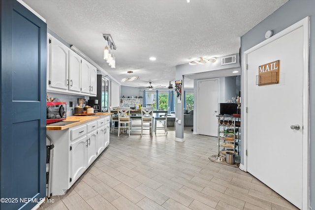 1167 Romaine Cir E, Jacksonville, FL 32225 - kitchen featuring a textured ceiling, white cabinets, a ceiling fan, and light wood-style floors