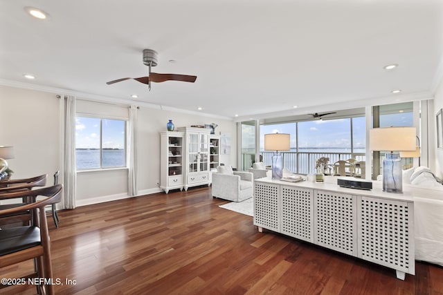 living area featuring ceiling fan, ornamental molding, wood finished floors, a water view, and baseboards