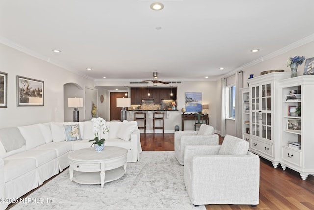 living area featuring dark wood-style flooring, recessed lighting, crown molding, arched walkways, and ceiling fan