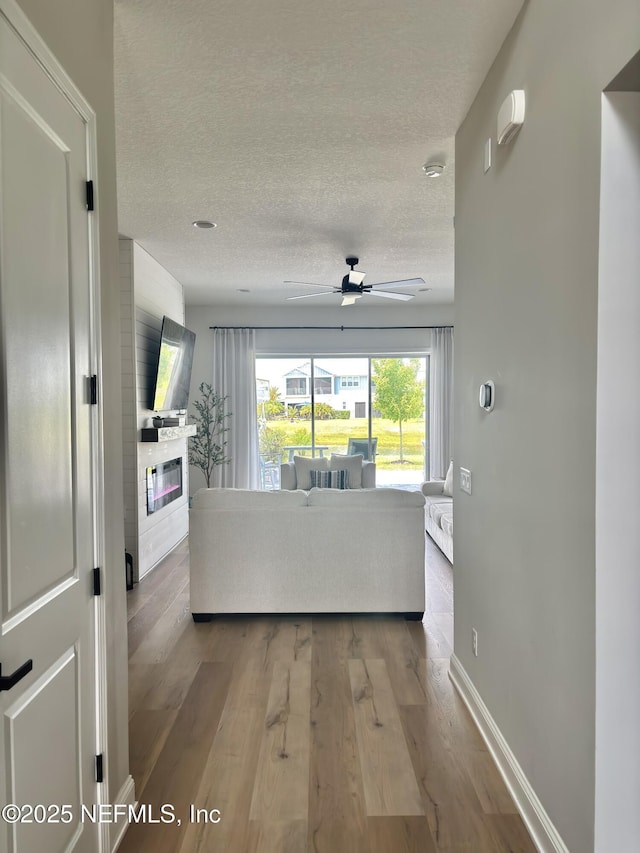 627 Rum Runner Way, Saint Johns, FL 32259 - living area featuring a textured ceiling, a large fireplace, a ceiling fan, and wood finished floors