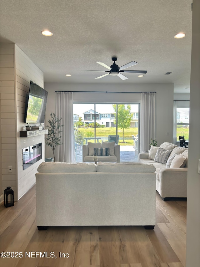 627 Rum Runner Way, Saint Johns, FL 32259 - living area featuring a textured ceiling, a glass covered fireplace, wood finished floors, a ceiling fan, and recessed lighting