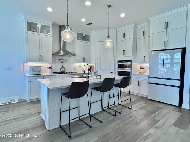 627 Rum Runner Way, Saint Johns, FL 32259 - kitchen with wall chimney exhaust hood, stainless steel appliances, white cabinetry, a kitchen bar, and light countertops