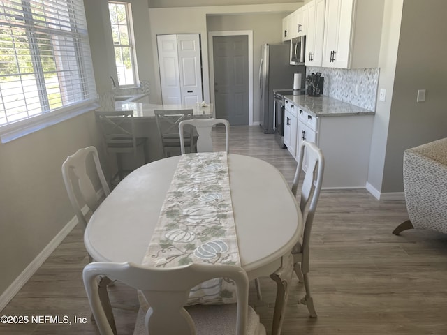 dining space featuring baseboards and light wood-style floors