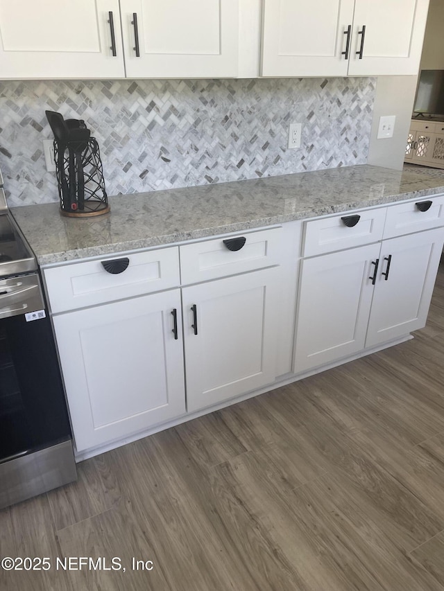 kitchen with range, white cabinetry, light stone counters, and tasteful backsplash