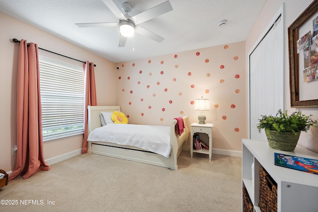 bedroom featuring light colored carpet, baseboards, a textured ceiling, and a ceiling fan