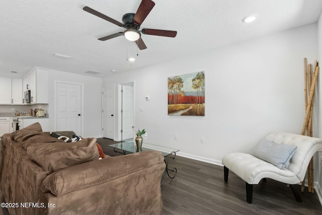 living area featuring baseboards, dark wood finished floors, ceiling fan, recessed lighting, and a textured ceiling