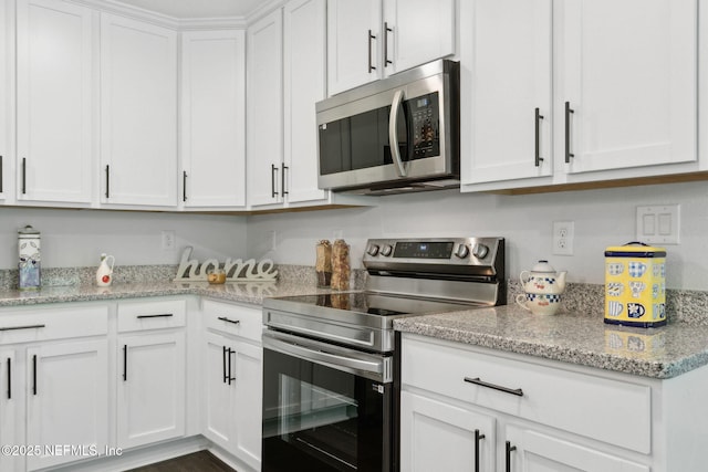 kitchen featuring stainless steel appliances, white cabinets, and light stone countertops