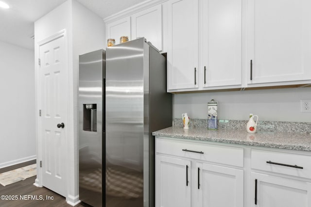 kitchen with stainless steel fridge, dark wood-style floors, white cabinets, and light stone counters