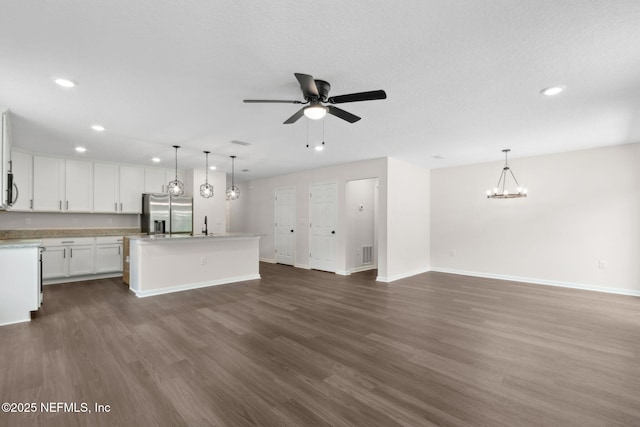 unfurnished living room featuring recessed lighting, baseboards, dark wood finished floors, a ceiling fan, and a chandelier