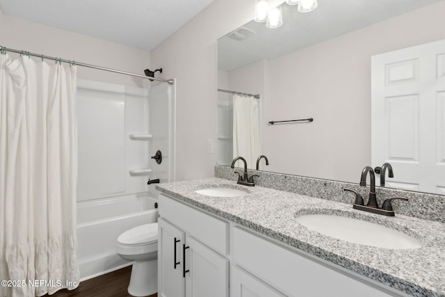 bathroom featuring toilet, double vanity, wood finished floors, and shower / tub combo