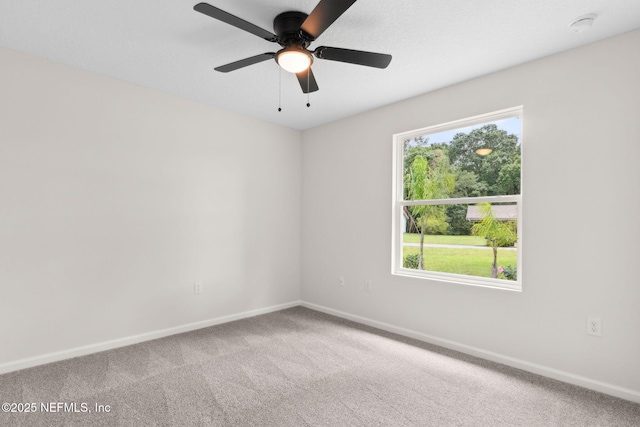 carpeted spare room with baseboards, ceiling fan, and a smoke detector