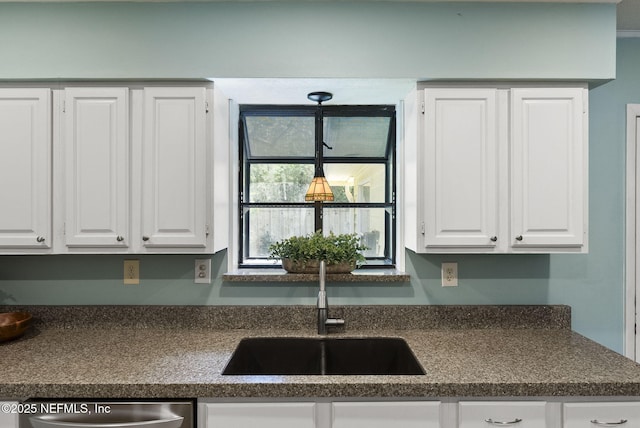 kitchen with dark countertops, a sink, white cabinetry, and stainless steel dishwasher