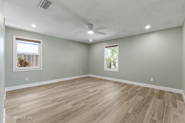 unfurnished room featuring a ceiling fan, light wood-style flooring, healthy amount of natural light, baseboards, and a textured ceiling