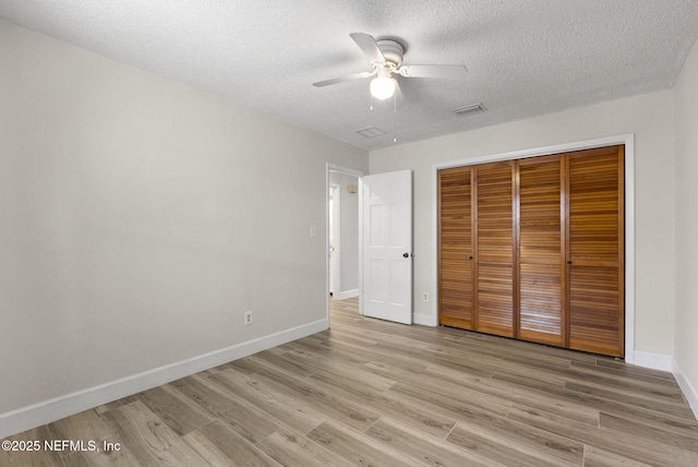 unfurnished bedroom with a textured ceiling, baseboards, a closet, light wood-style floors, and ceiling fan