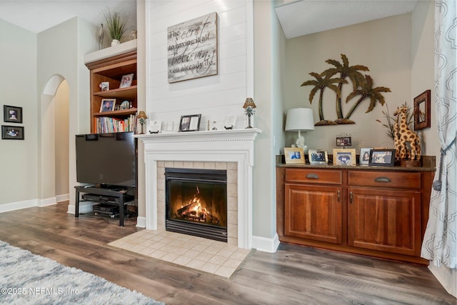 400 N Landguard Rd, Saint Augustine, FL 32092 - living room featuring a tile fireplace, dark wood-style flooring, arched walkways, and baseboards