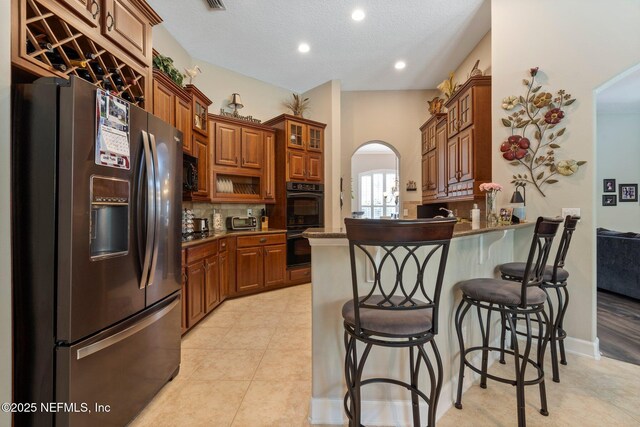 400 N Landguard Rd, Saint Augustine, FL 32092 - kitchen with black appliances, brown cabinets, a breakfast bar area, a peninsula, and backsplash