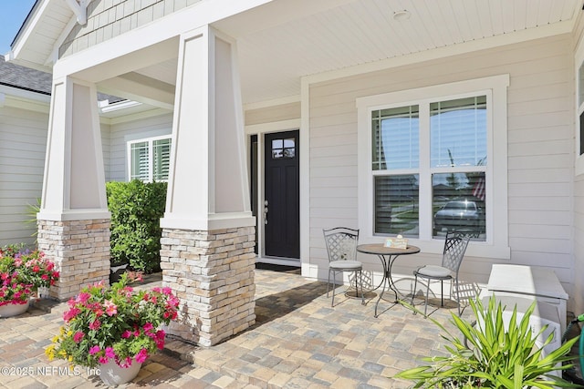entrance to property with a porch and stone siding