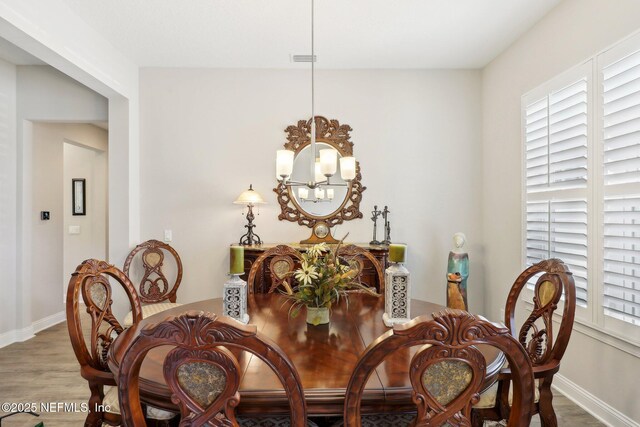 dining area with a chandelier, wood finished floors, plenty of natural light, and baseboards
