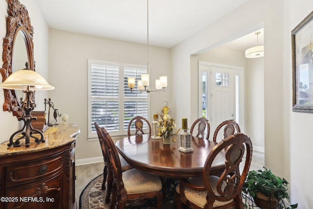 dining room with wood finished floors, plenty of natural light, a chandelier, and baseboards