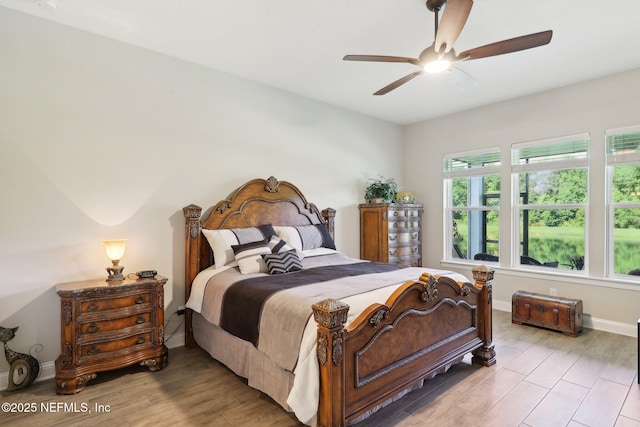 bedroom featuring light wood-type flooring, a ceiling fan, and baseboards