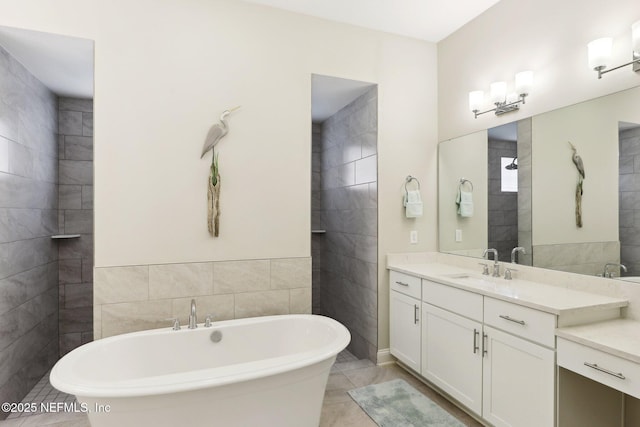 full bathroom with a freestanding tub, vanity, tile walls, and tile patterned floors