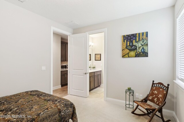 bedroom featuring baseboards, light carpet, and connected bathroom