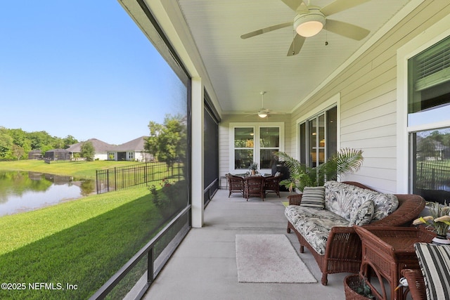 sunroom featuring a ceiling fan, a water view, and outdoor lounge area