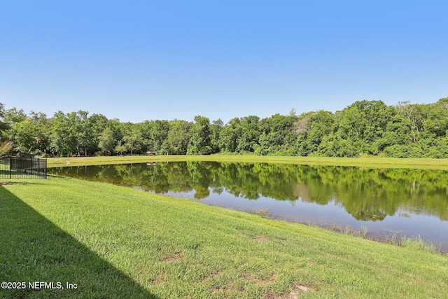 water view featuring a forest and fence