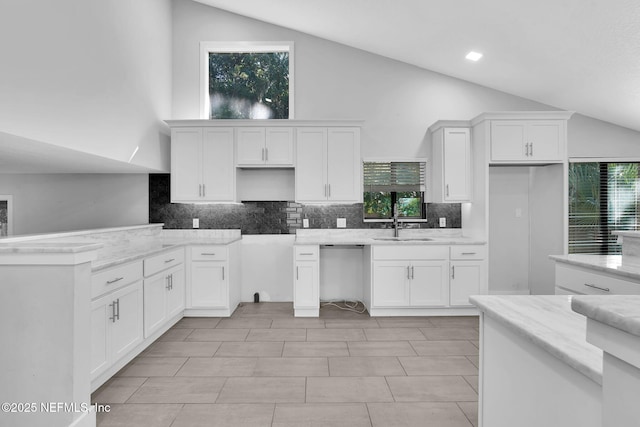 2032 Sandpiper Pt, Neptune Beach, FL 32266 - kitchen featuring backsplash, white cabinetry, dishwashing machine, high vaulted ceiling, and light stone counters