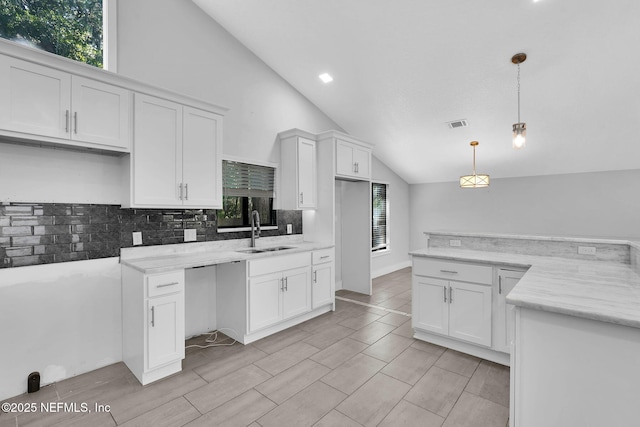 2032 Sandpiper Pt, Neptune Beach, FL 32266 - kitchen featuring vaulted ceiling, backsplash, white cabinets, pendant lighting, and recessed lighting