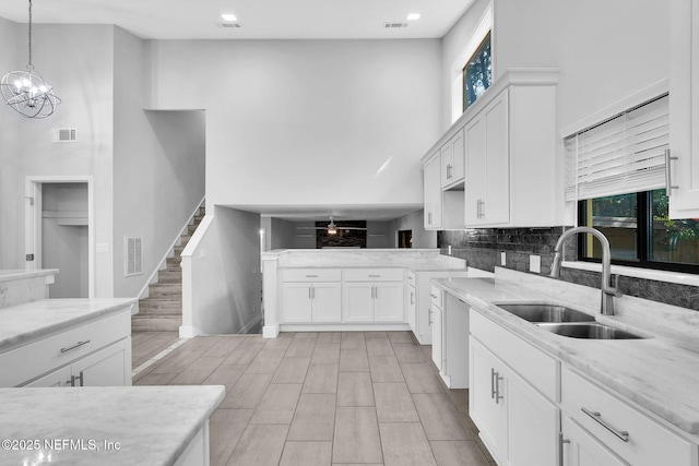 2032 Sandpiper Pt, Neptune Beach, FL 32266 - kitchen with a high ceiling, white cabinets, light stone counters, tasteful backsplash, and pendant lighting