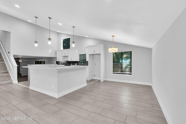 2032 Sandpiper Pt, Neptune Beach, FL 32266 - kitchen featuring vaulted ceiling, white cabinets, a center island, decorative light fixtures, and light countertops