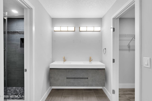 2032 Sandpiper Pt, Neptune Beach, FL 32266 - full bathroom featuring a spacious closet, a textured ceiling, and double vanity