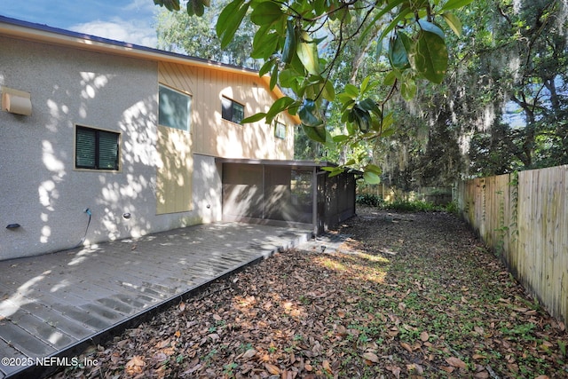 2032 Sandpiper Pt, Neptune Beach, FL 32266 - rear view of property featuring a sunroom, a fenced backyard, a deck, and stucco siding