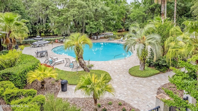 community pool with view of wooded area and a patio
