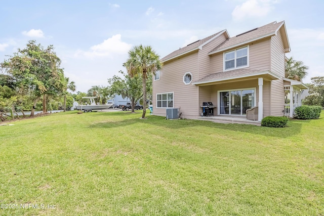back of property featuring cooling unit, a yard, a shingled roof, and a patio