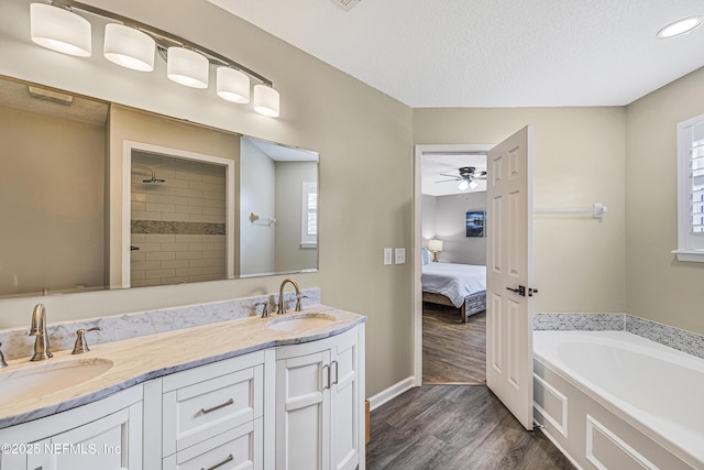 bathroom with wood finished floors, a textured ceiling, double vanity, a garden tub, and ensuite bath