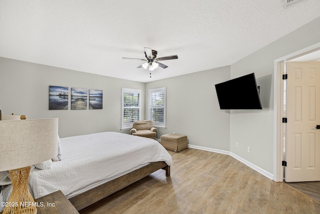 bedroom featuring light wood-style flooring, baseboards, ceiling fan, and a textured ceiling