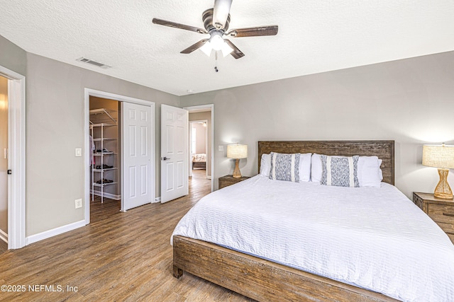 bedroom featuring wood finished floors, baseboards, a closet, a textured ceiling, and ceiling fan