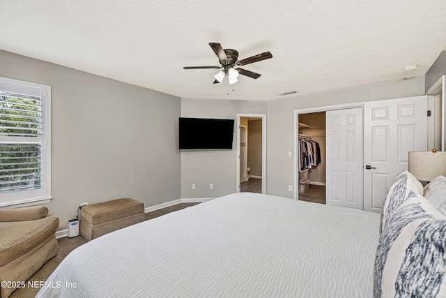 bedroom featuring baseboards, a closet, a ceiling fan, and a walk in closet
