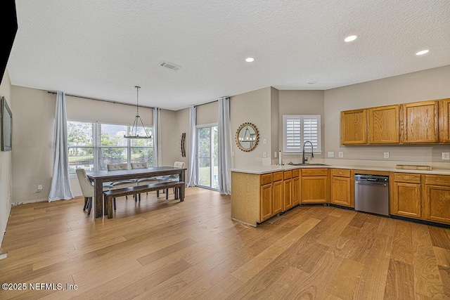 kitchen with dishwasher, a sink, light wood-style floors, light countertops, and a textured ceiling