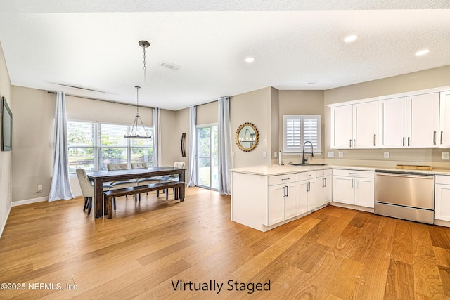 kitchen with stainless steel dishwasher, white cabinetry, light countertops, a sink, and recessed lighting