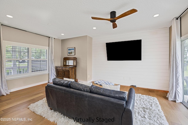 living area with a ceiling fan, wood finished floors, wood walls, a textured ceiling, and recessed lighting