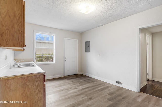 330 W 26th St, Jacksonville, FL 32206 - laundry room featuring electric panel, cabinet space, a textured ceiling, light wood-style flooring, and baseboards