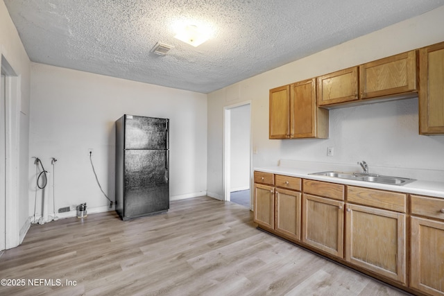 330 W 26th St, Jacksonville, FL 32206 - kitchen with freestanding refrigerator, a sink, light countertops, light wood-style floors, and a textured ceiling