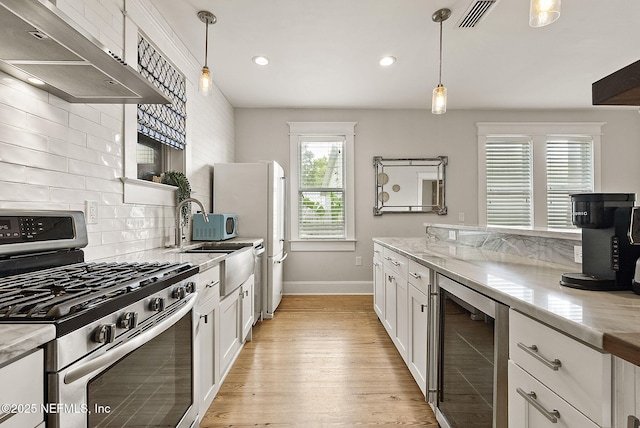 206 Cabeza St, Saint Augustine, FL 32080 - kitchen featuring stainless steel range with gas stovetop, wine cooler, exhaust hood, baseboards, and light wood-style flooring