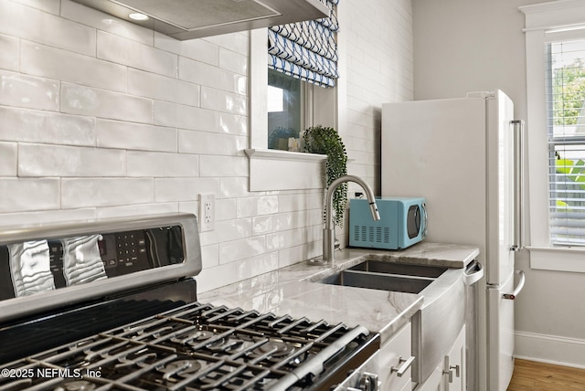 206 Cabeza St, Saint Augustine, FL 32080 - kitchen featuring stainless steel gas range oven, light stone countertops, backsplash, white cabinetry, and exhaust hood